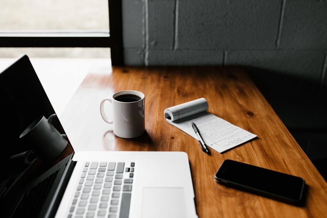 MacBook Pro, white ceramic mug and black smartphone on a table (©Unsplash / Andrew Neel)